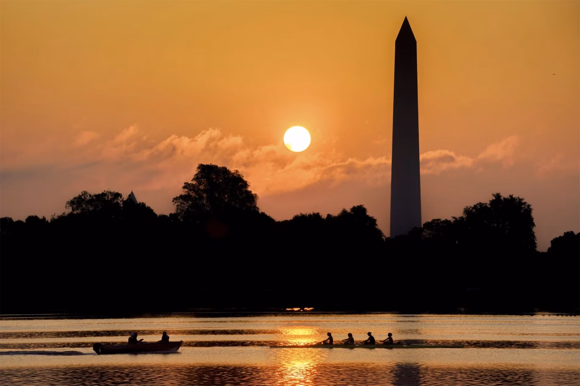 Đội chèo thuyền di chuyển trên sông Potomac đoạn qua Đài tưởng niệm Washington trong lúc mặt trời mọc, ngày 20/7/2023. (Ảnh: AP)