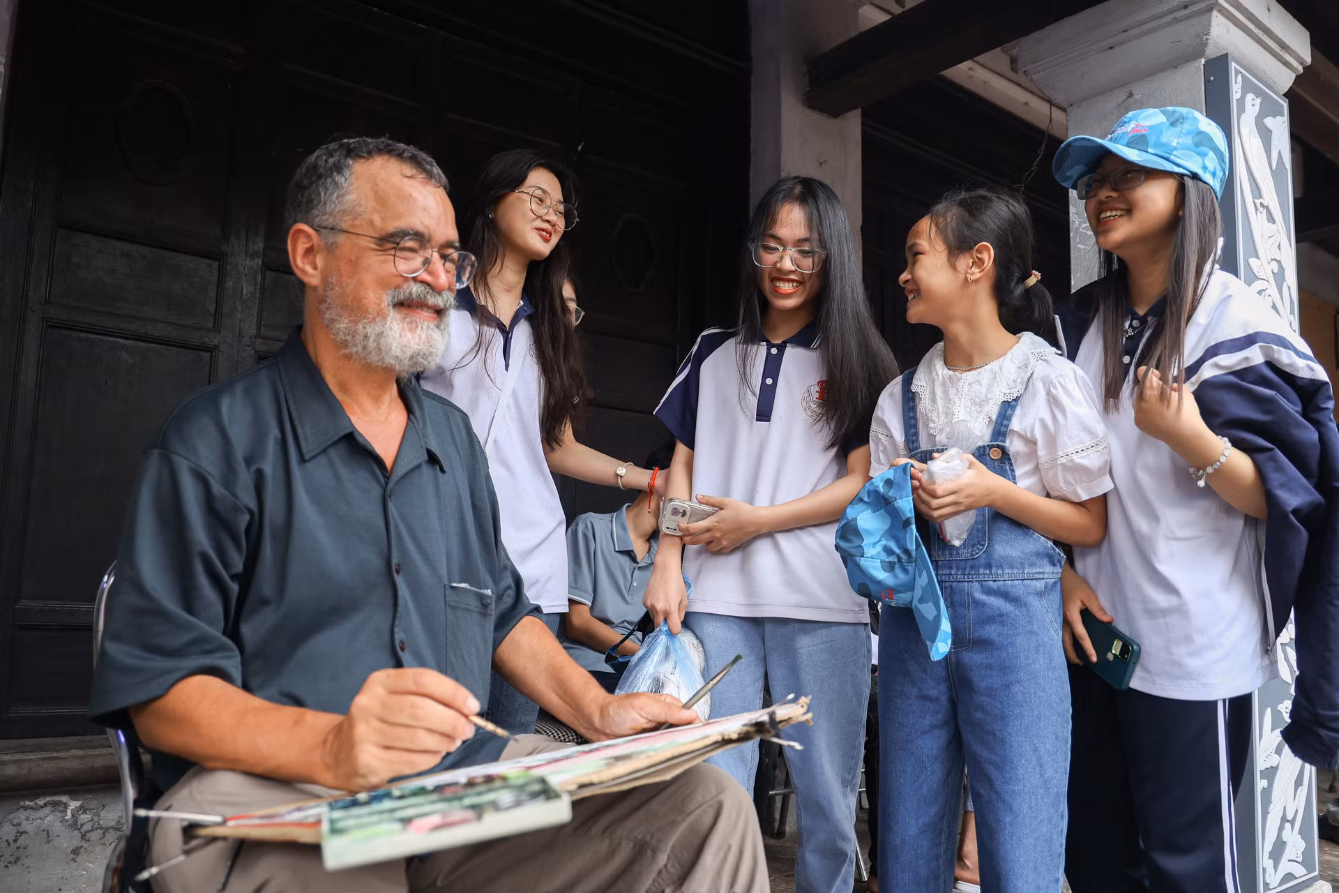 Các em học sinh thích thú khi bắt gặp vị "du khách" đang vẽ tranh tại Văn Miếu-Quốc Tử Giám.