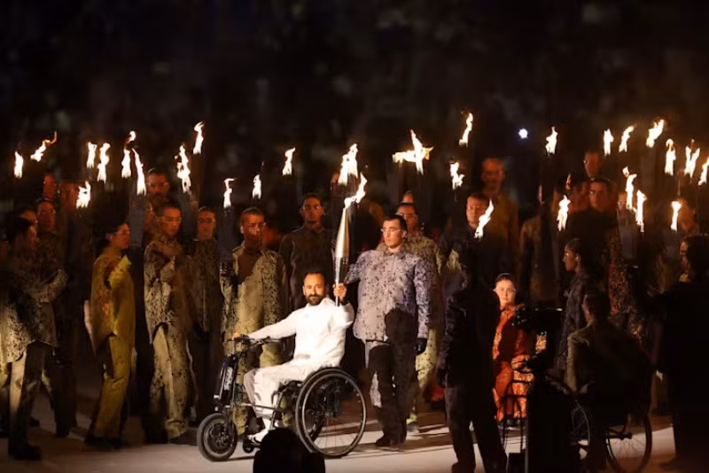 Ngọn lửa Paralympic được cầm trên tay một vận động viên khuyết tật tiến vào sân khấu, đi cùng phía sau là hơn 150 vũ công cũng mang theo ngọn đuốc rực lửa. (Ảnh: Paris 2024)