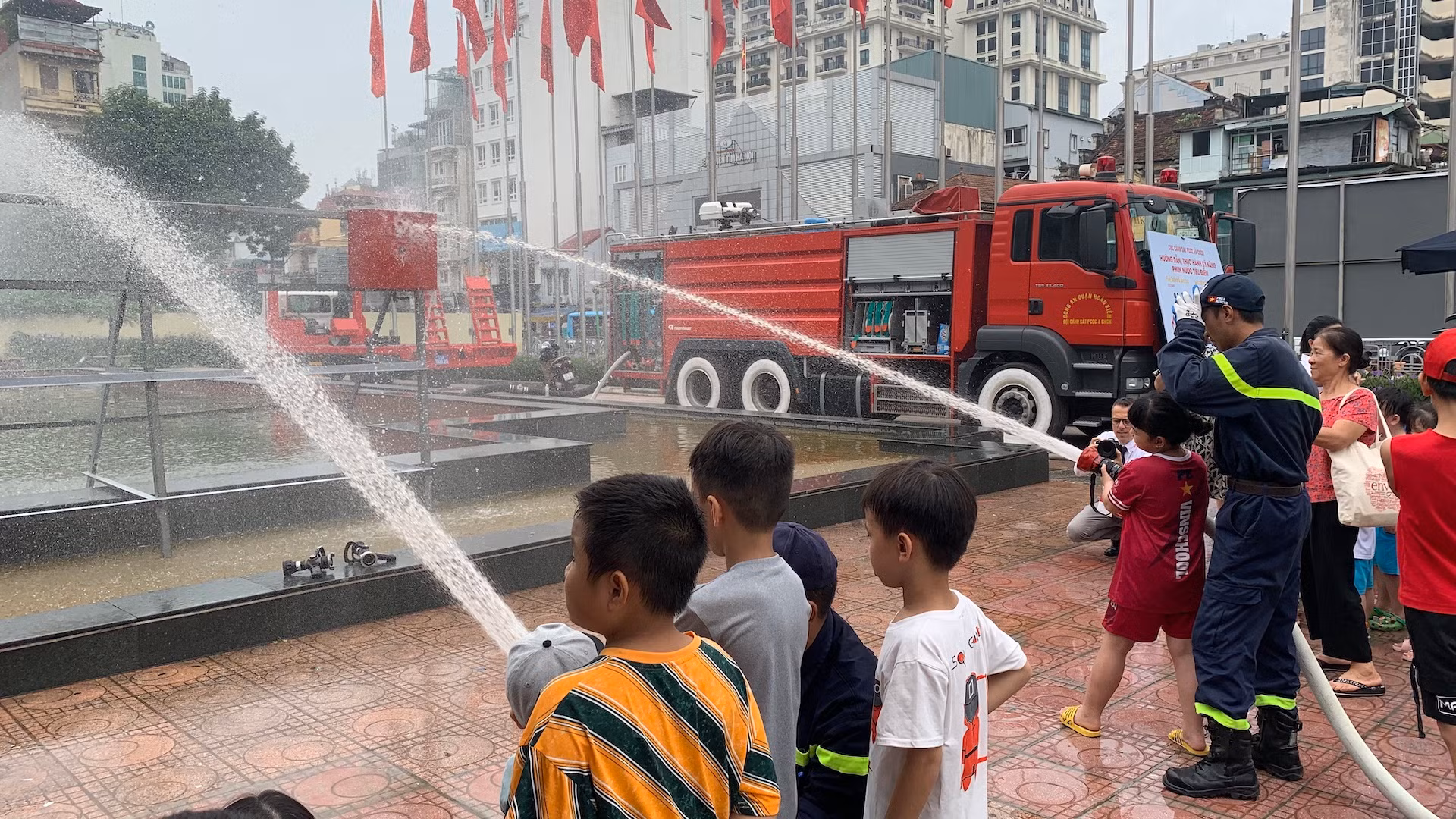 Các em nhỏ được hướng dẫn trải nghiệm phun nước cứu hỏa.