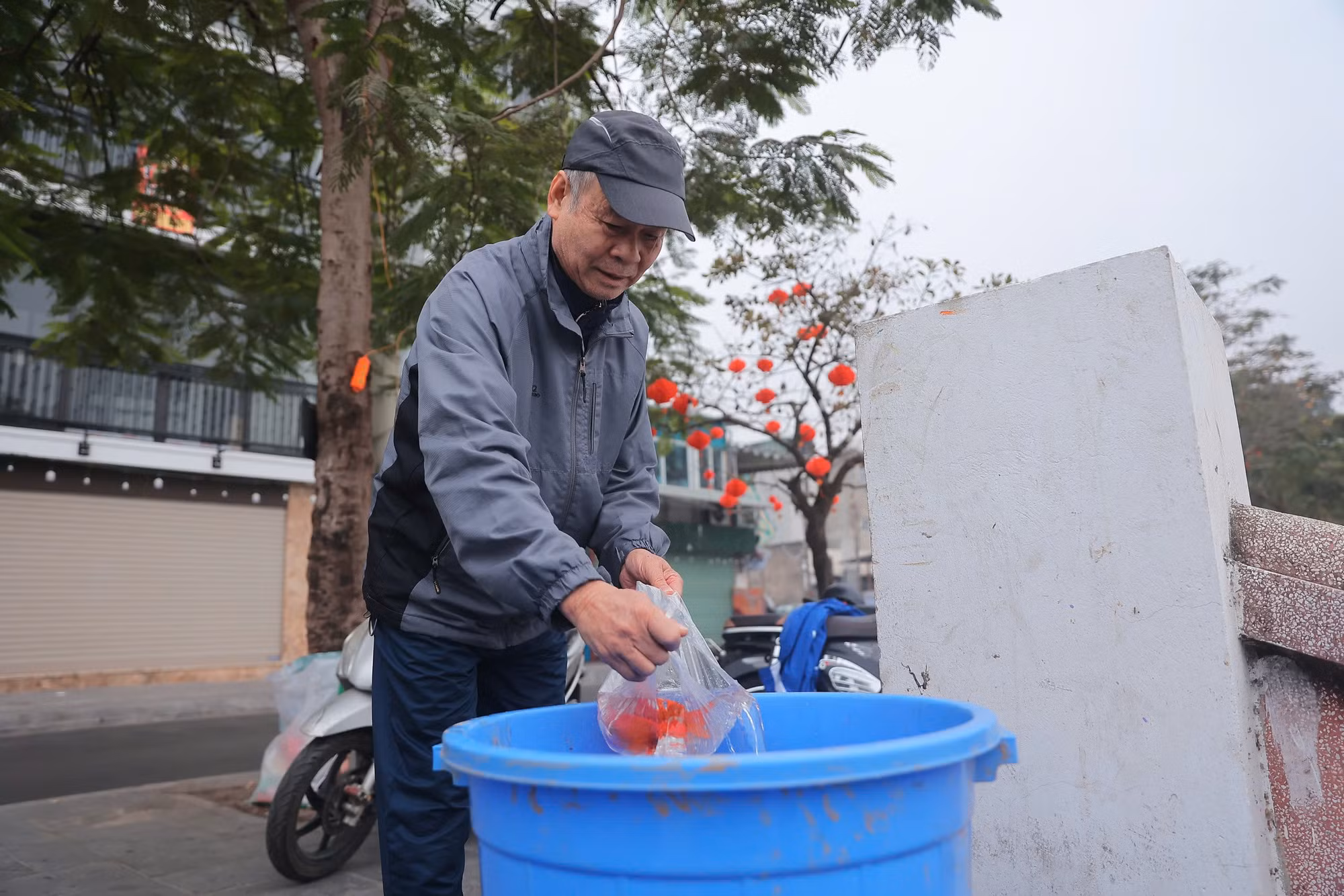 Một người dân đang thả cá vào thùng ven hồ Tây.