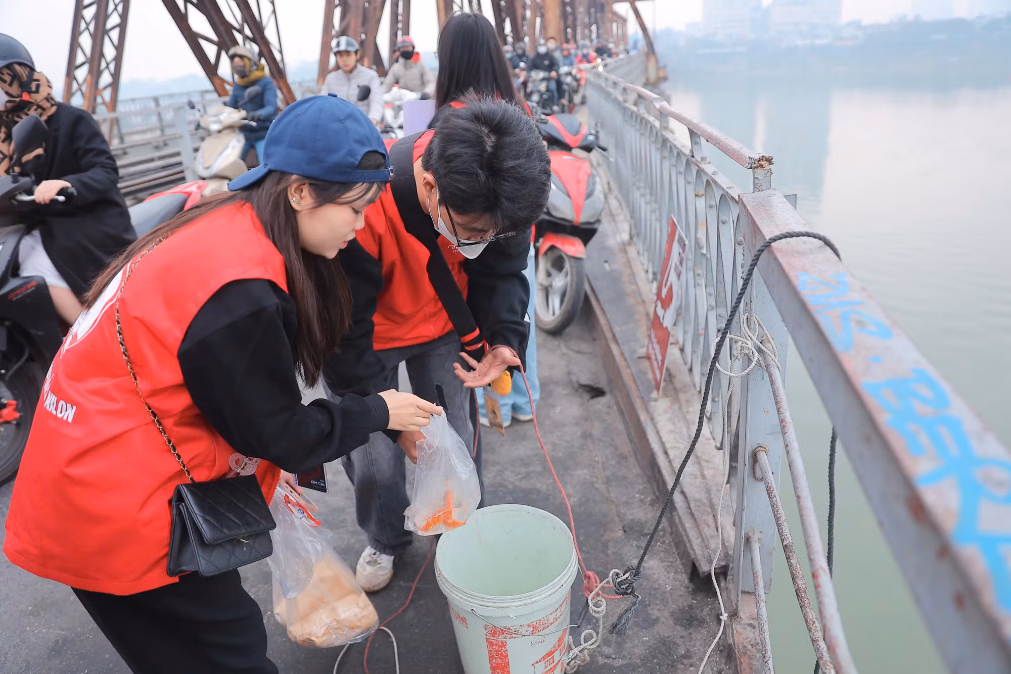 Tại khu vực cầu Long Biên, nhóm tình nguyện viên đã có mặt từ sớm để hỗ trợ người dân thả cá chép, giữ gìn vệ sinh môi trường.