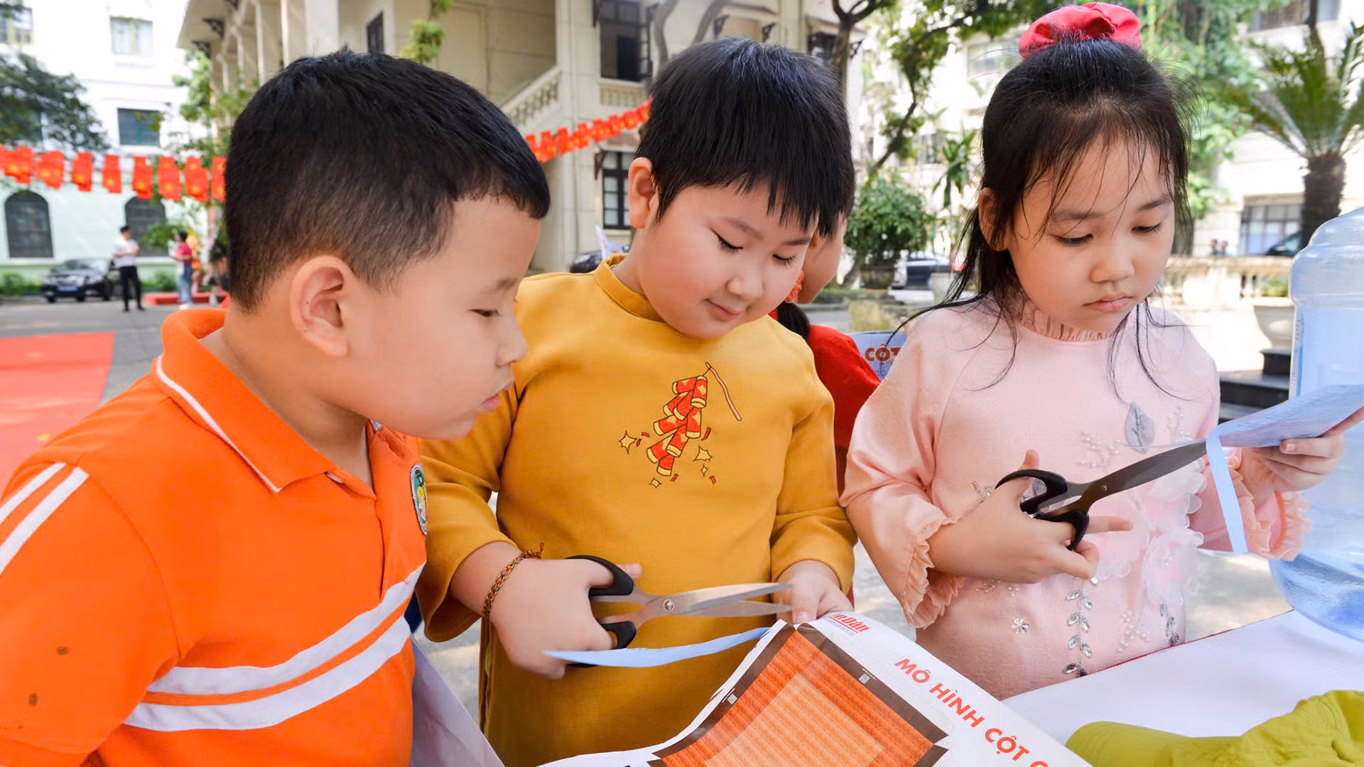 Các học sinh Trường tiểu học Tràng An cắt dán mô hình Cột cờ Hà Nội tại triển lãm của Báo Nhân Dân. (Ảnh THẾ ĐẠI)