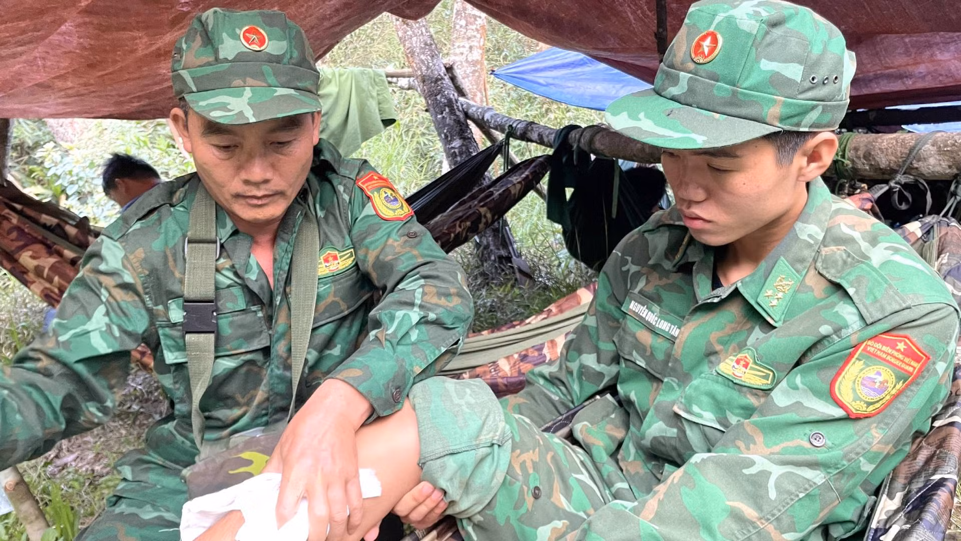 Tranh thủ lúc nghỉ ngơi, Thiếu tá Trần Xuân Hanh, cán bộ Quân y Đồn Biên phòng cửa khẩu quốc tế Cha Lo xoa bóp chân cho một đồng chí bị sưng tấy trong chuyến hành quân dài ngày nhiều vất vả. Tranh thủ lúc nghỉ ngơi, Thiếu tá Trần Xuân Hanh, cán bộ Quân y Đồn Biên phòng cửa khẩu quốc tế Cha Lo xoa bóp chân cho một đồng chí bị sưng tấy trong chuyến hành quân dài ngày nhiều vất vả.