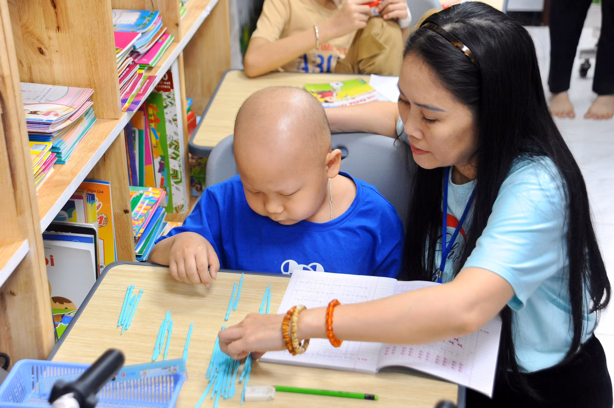 Chị Mai ân cần hướng dẫn bài tập cho một trẻ mắc ung thư.