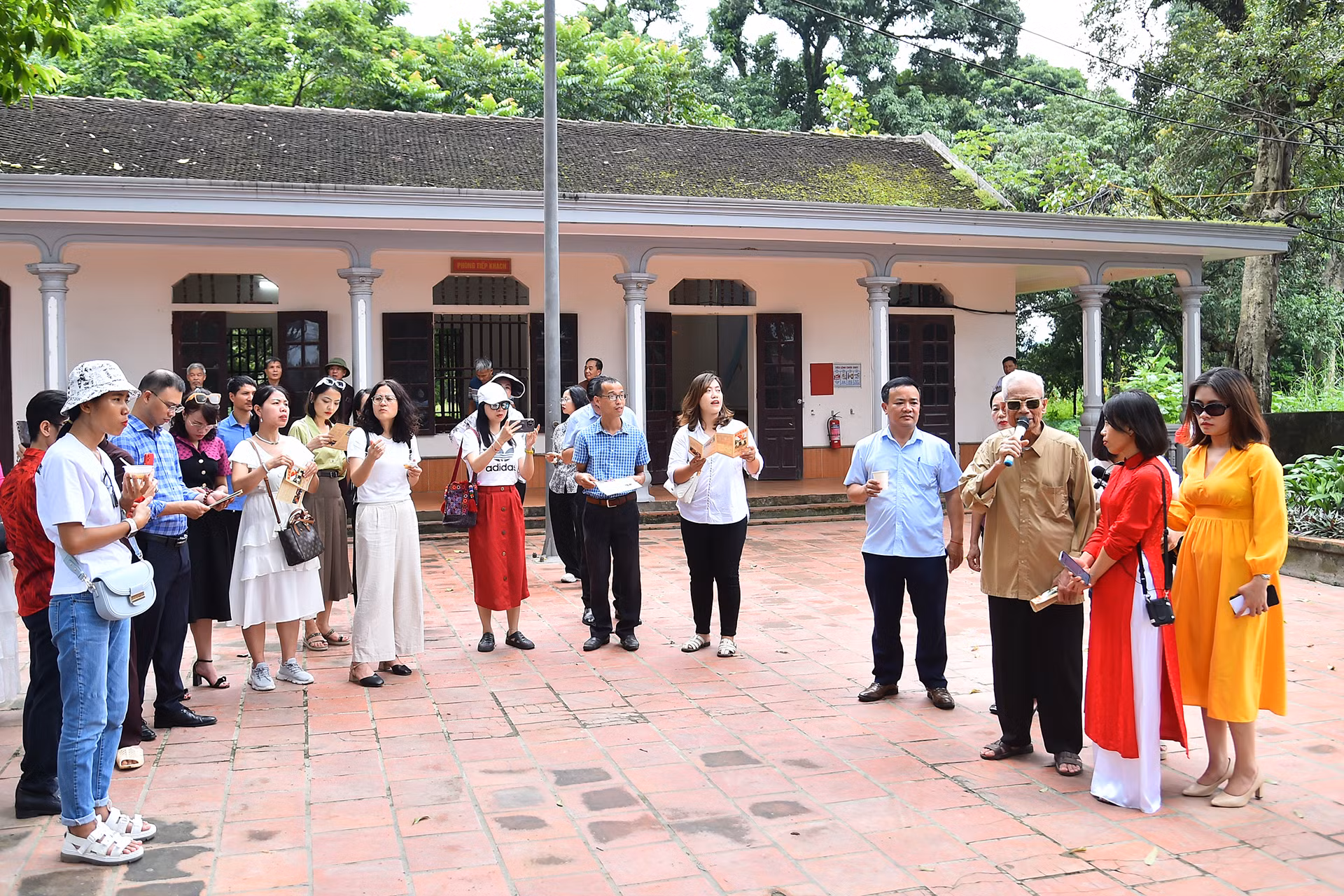 Du khách lắng nghe cụ cao niên trong làng giới thiệu về lịch sử Di tích lịch sử - văn hóa cấp quốc gia Đền Đức Thánh Cả.