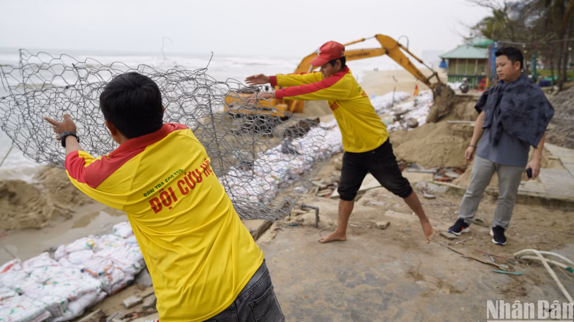 Lực lượng cứu hộ biển Đà Nẵng đang triển khai dây thép gai bao quanh các bao tải cát. (Ảnh: ANH ĐÀO) Lực lượng cứu hộ biển Đà Nẵng đang triển khai dây thép gai bao quanh các bao tải cát. (Ảnh: ANH ĐÀO)