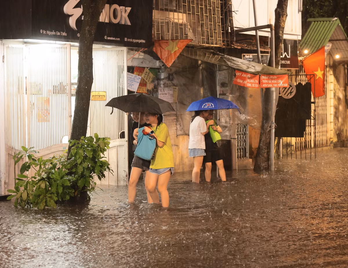 Việc di chuyển của người dân sống trên phố Nguyễn Gia Thiều, quận Hoàn Kiếm bị ảnh hưởng lớn do ngập. (Ảnh: Hoàng Hiếu/TTXVN)