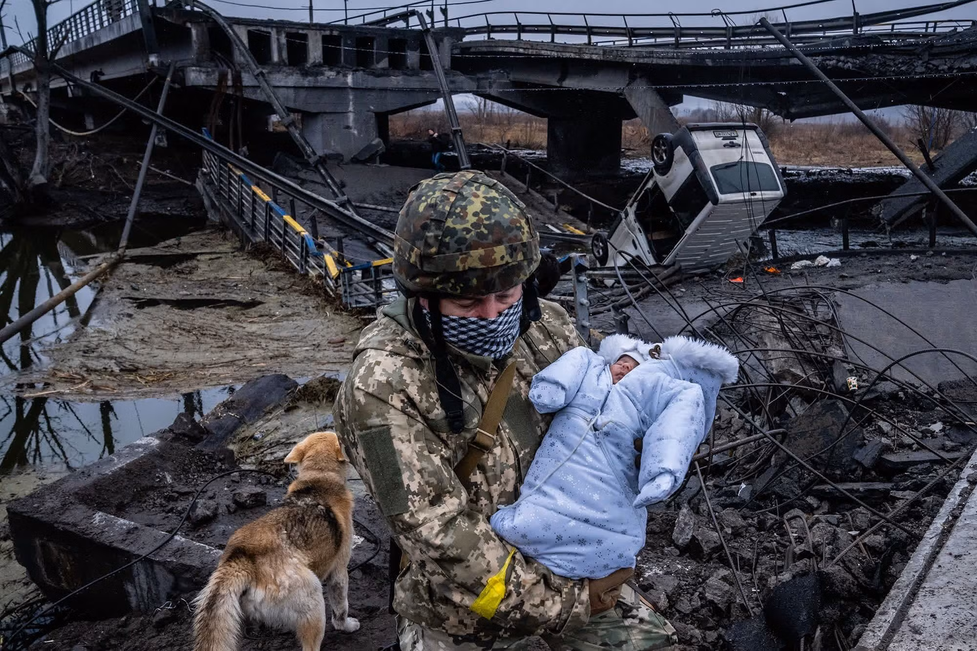 Binh sĩ Ukraine đưa 1 em bé sơ sinh đi qua cây cầu đã bị phá hủy ở ngoại ô thủ đô Kiev, ngày 3/3. (Ảnh: CNN) Binh sĩ Ukraine đưa 1 em bé sơ sinh đi qua cây cầu đã bị phá hủy ở ngoại ô thủ đô Kiev, ngày 3/3. (Ảnh: CNN)