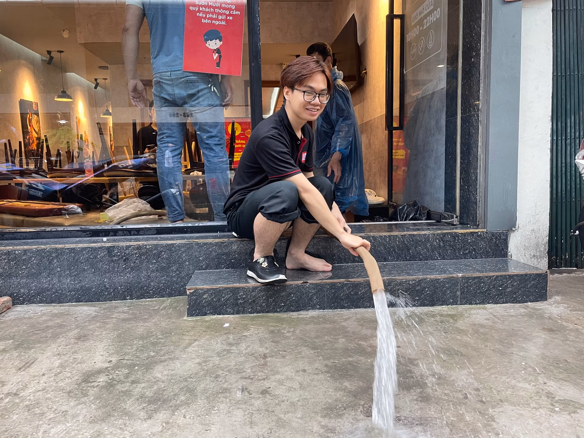 Nhân viên một quán cafe bơm nước ra bên ngoài. Nhân viên một quán cafe bơm nước ra bên ngoài.