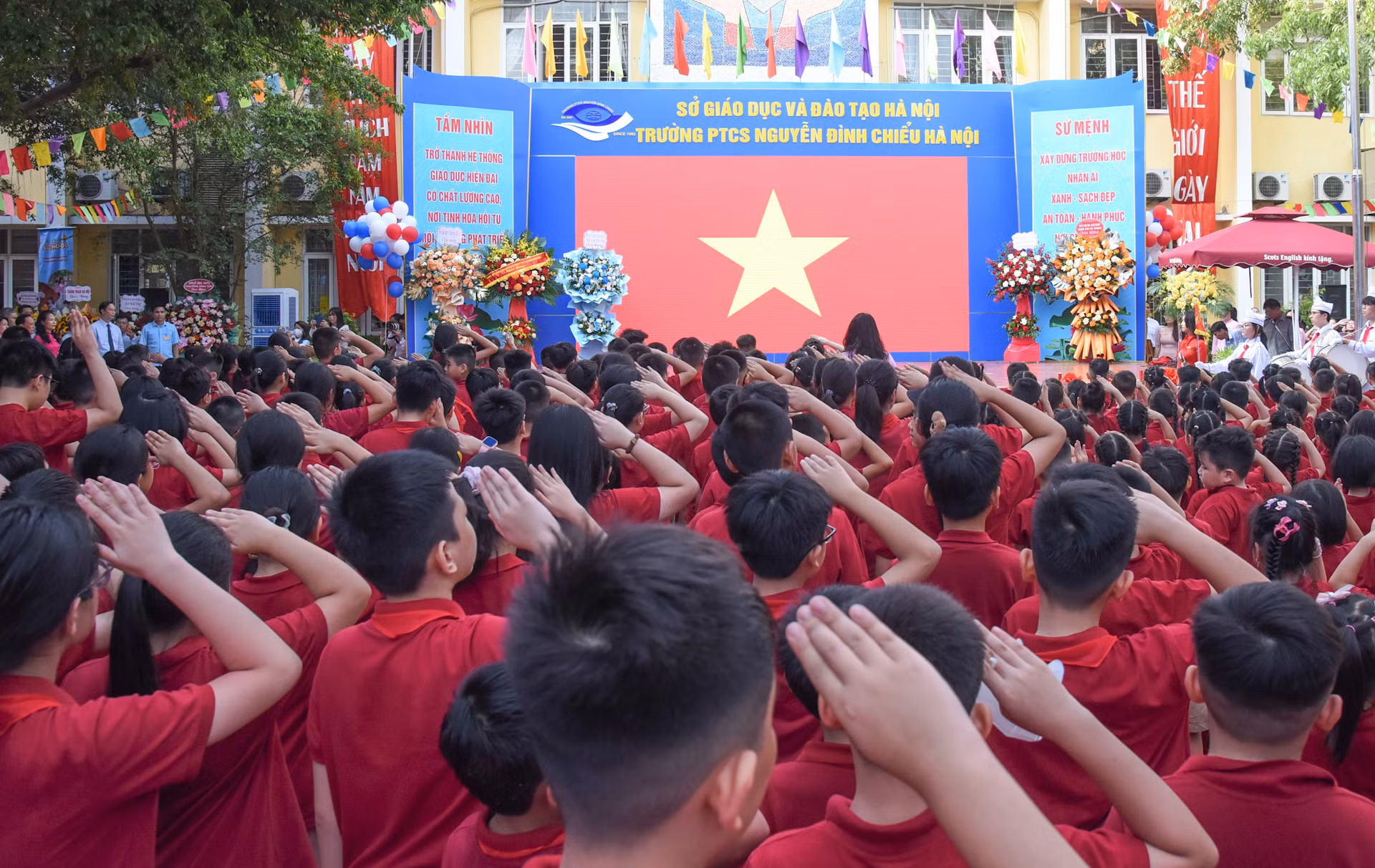 Các đại biểu cùng các thầy cô giáo, các em học sinh thực hiện nghi thức chào cờ tại buổi lễ.