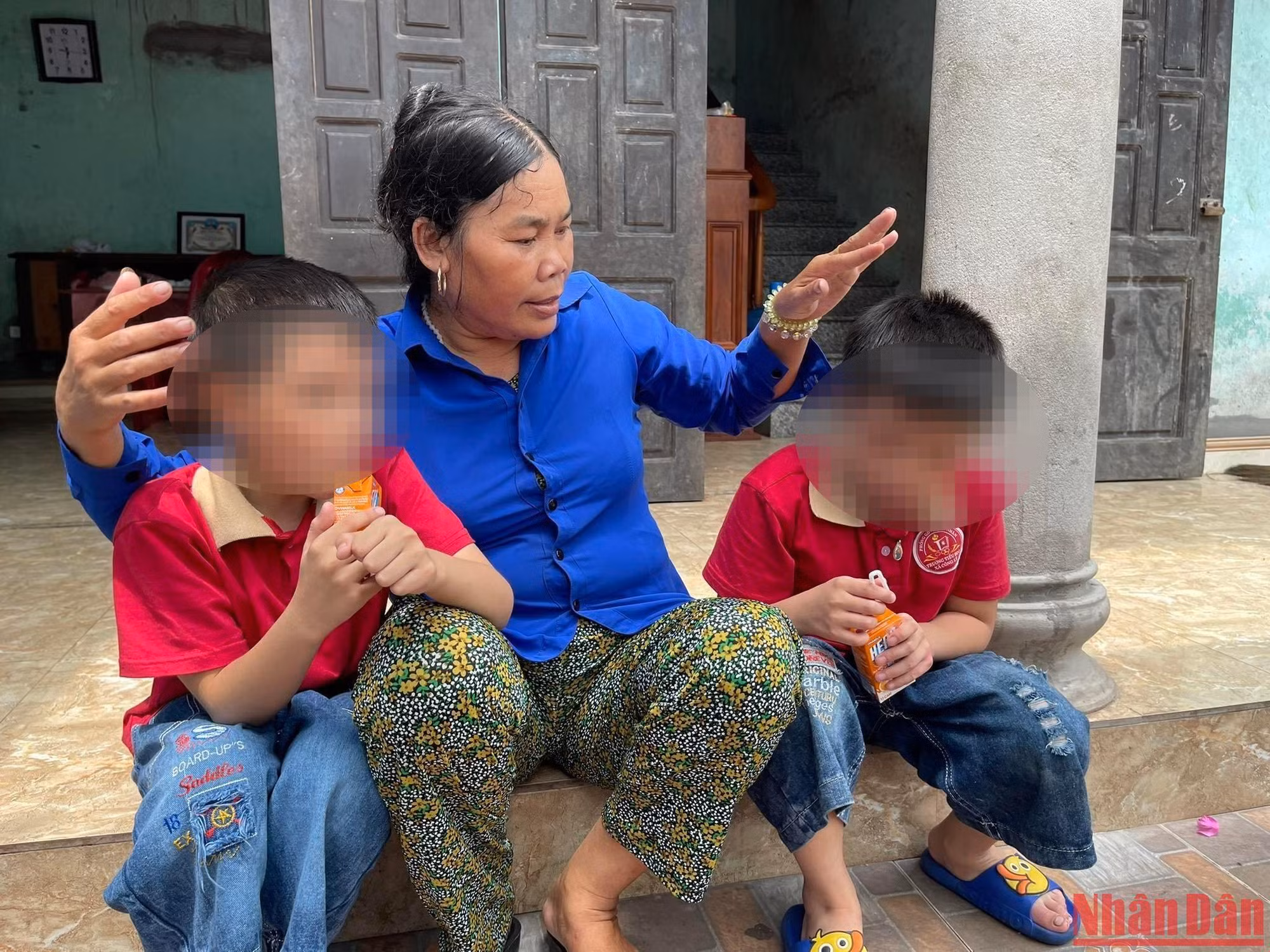 Bà Cúc và 2 người con không chung huyết thống Bảo Q., Bảo K. bên hiên nhà. 