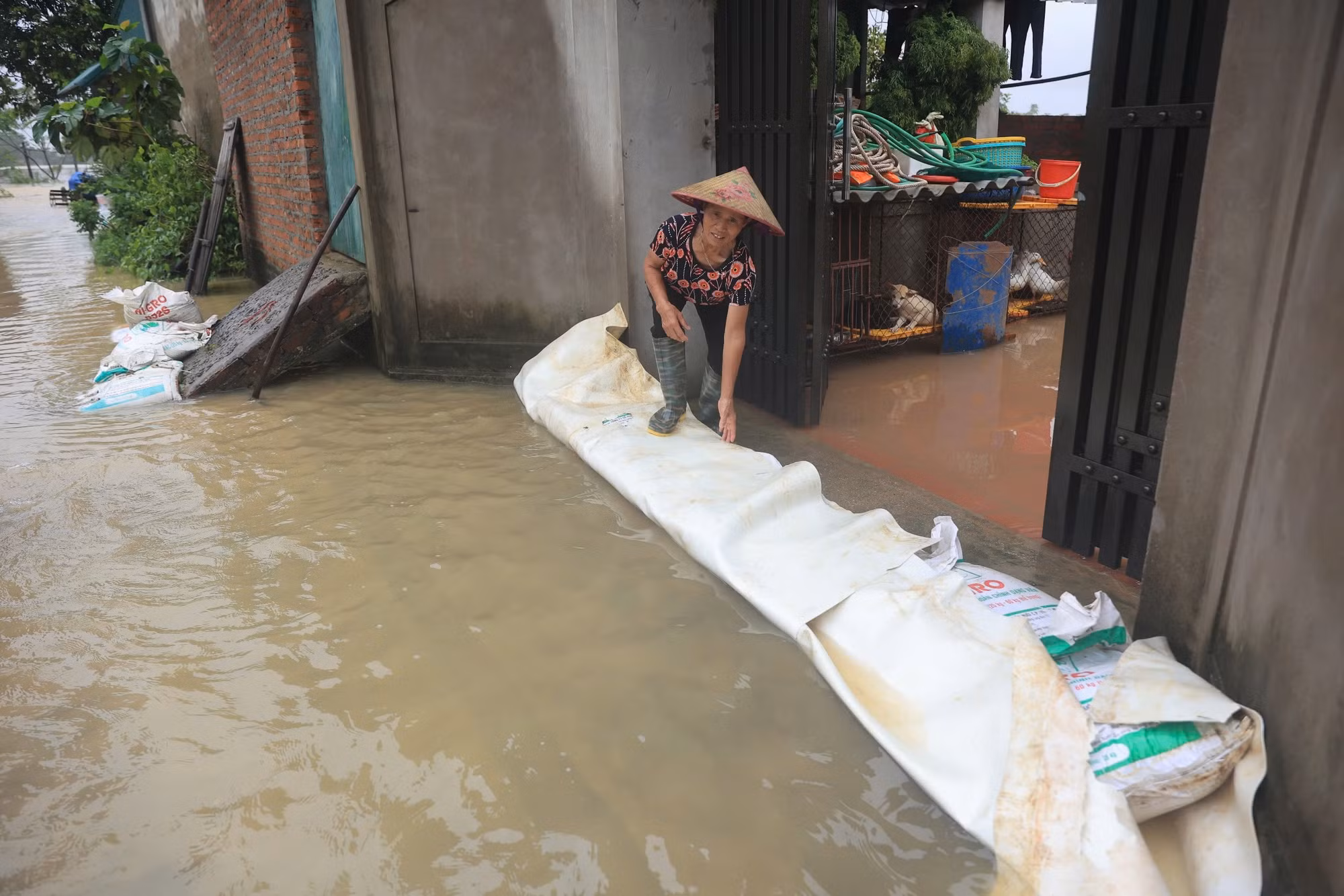 Người dân dùng bao cát chặn trước cửa nhà để ngăn nước tràn vào nhà. Người dân dùng bao cát chặn trước cửa nhà để ngăn nước tràn vào nhà.