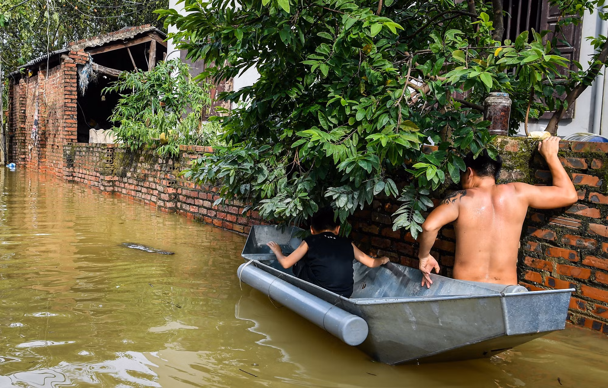 Dù đã rút bớt, nhưng nước lũ vẫn gần ngập bức tường cao tới hơn 2m.