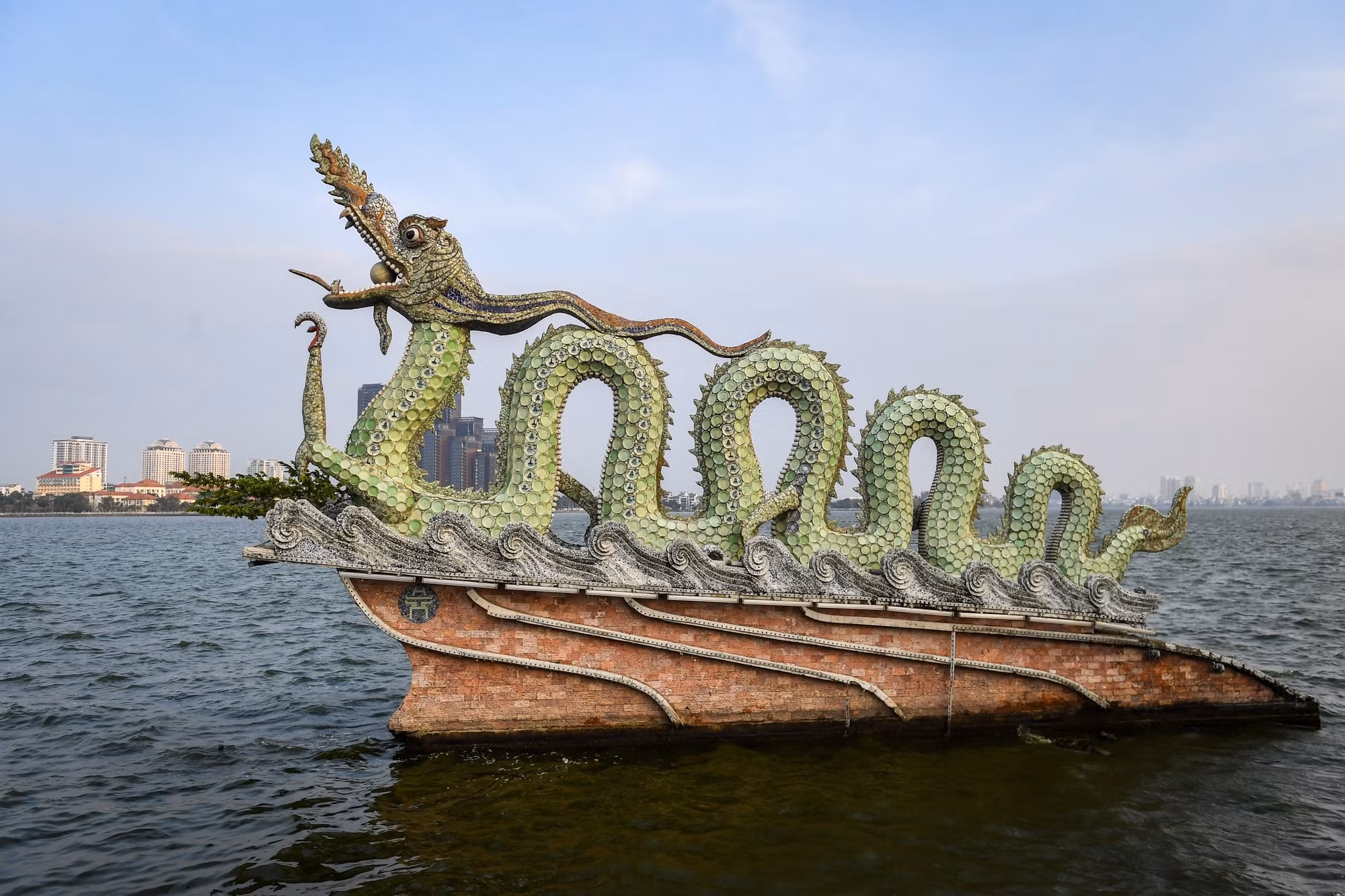 Phía ngoài thân rồng được trang trí bằng nhiều mảnh gốm sứ, ấm chén, chai lọ nung ở nhiệt độ 1.300 độ C. Phía ngoài thân rồng được trang trí bằng nhiều mảnh gốm sứ, ấm chén, chai lọ nung ở nhiệt độ 1.300 độ C.