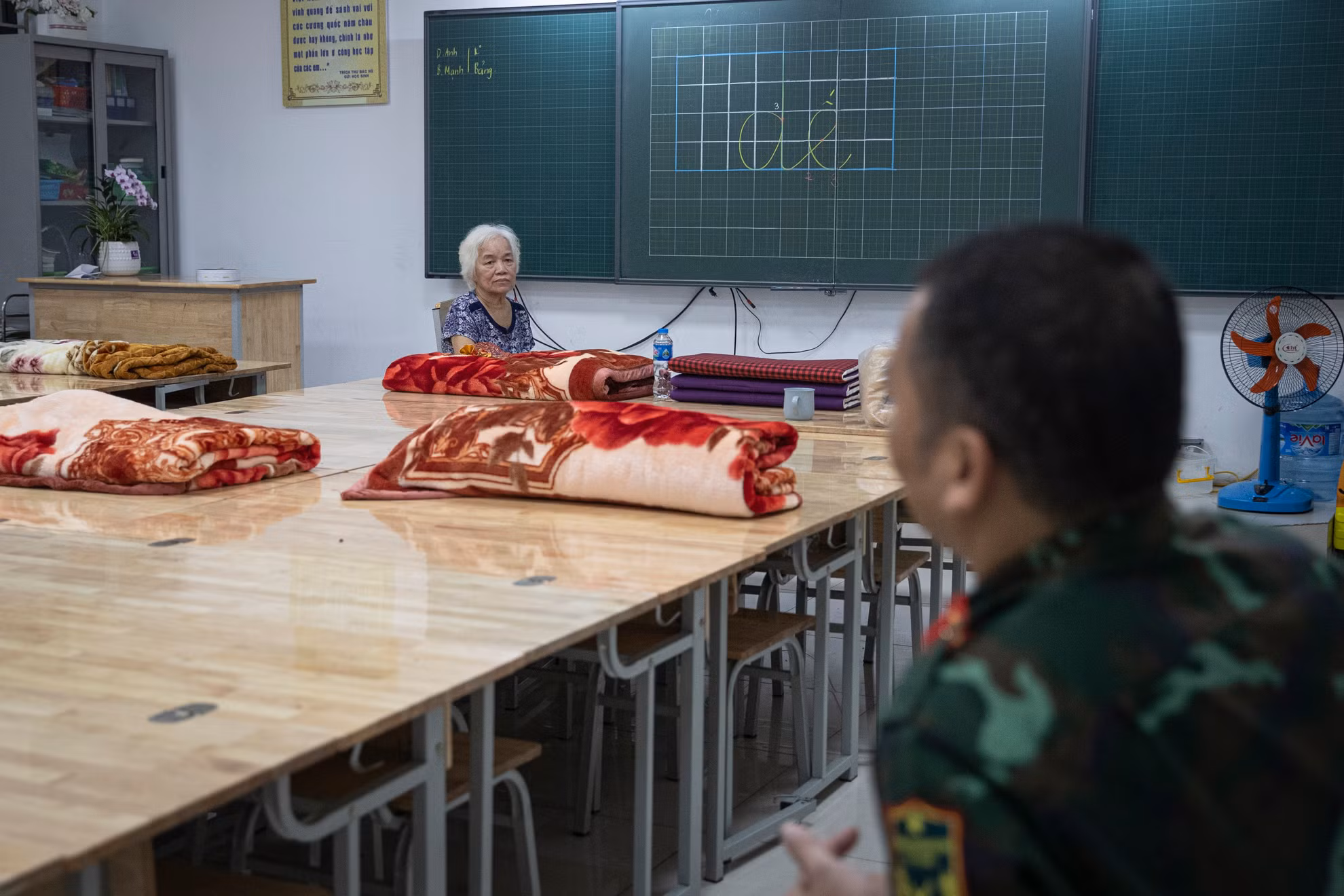 Phía bên trong, các bàn học được ghép thành những chiếc giường tạm thời. Chăn, màn, gối cũng được chuẩn bị sẵn sàng.