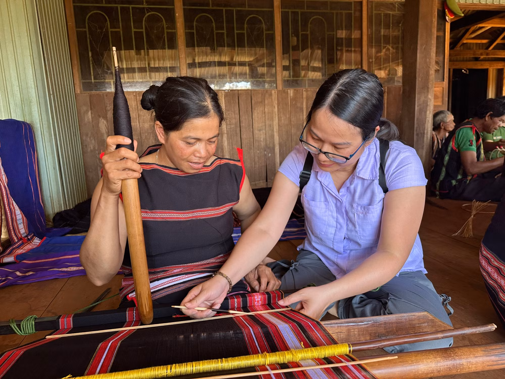 Hướng dẫn du khách trải nghiệm dệt vải. (Ảnh THI PHONG) Hướng dẫn du khách trải nghiệm dệt vải. (Ảnh THI PHONG)