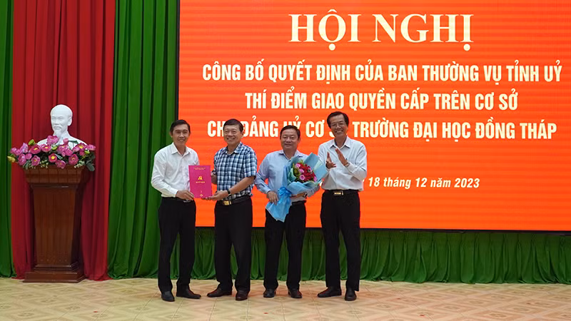 Bí thư Đảng ủy Trường đại học Đồng Tháp Trương Tấn Đạt và Hiệu trưởng Trường đại học Đồng Tháp Hồ Văn Thống nhận Quyết định, hoa của Ban Thường vụ Tỉnh ủy Đồng Tháp. (Ảnh: HỮU NGHĨA)