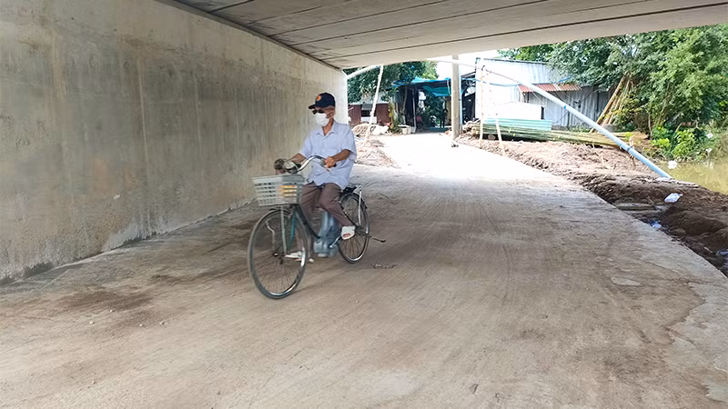 Đường dân sinh đi ngang qua khoảng tĩnh không giữa nhịp mố và trụ cầu đã được làm bằng đường bê-tông. (Ảnh: HỮU NGHĨA)