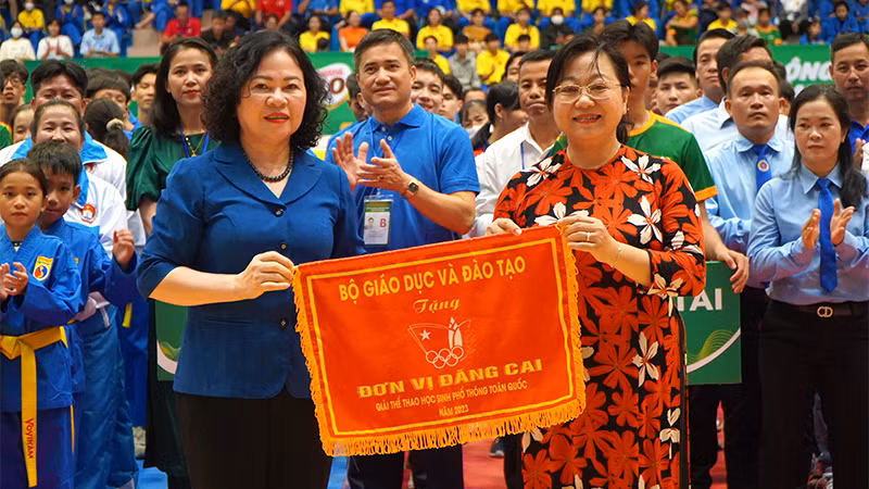 Thứ trưởng Giáo dục và Đào tạo Ngô Thị Minh trao cờ lưu niệm cho Giám đốc Sở Giáo dục và Đào tạo Nguyễn Thúy Hà, đại diện địa phương đăng cai