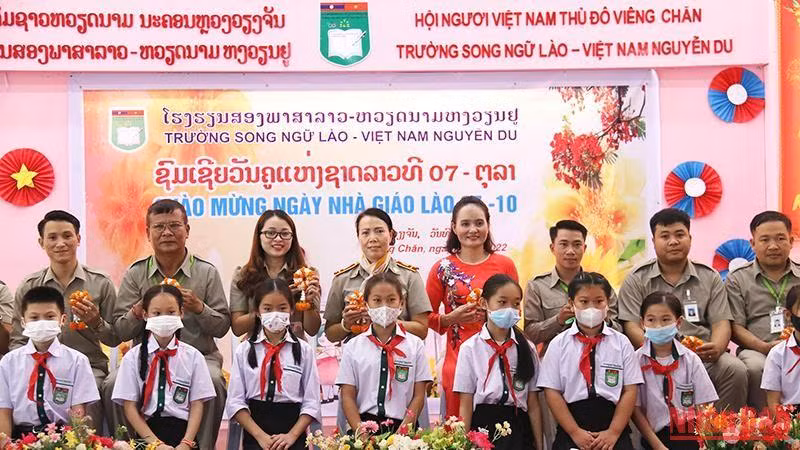 Các em học sinh Trường song ngữ Lào-Việt Nam Nguyễn Du tặng hoa tri ân các thầy, cô giáo nhân Ngày nhà giáo quốc gia Lào. (Ảnh: Hải Tiến)