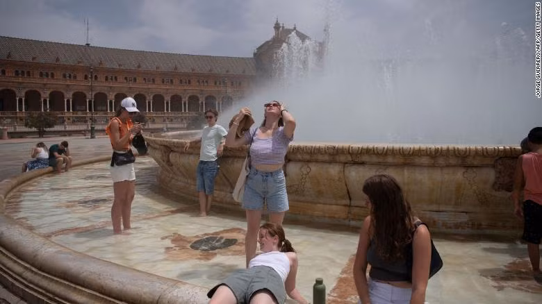 Người dân giải nhiệt ở đài phun trong đợt nắng nóng ở Seville, Tây Ban Nha. (Ảnh: CNN)