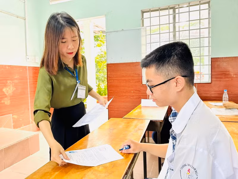 Cán bộ coi thi phát giấy thi cho thí sinh.