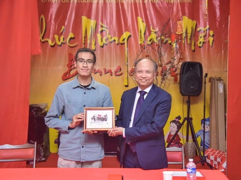 Đại sứ Đinh Toàn Thắng trao tặng bức tranh tem Chủ tịch Hồ Chí Minh do Bưu điện Pháp phát hành nhân dịp kỷ niệm 100 năm Người đặt chân đến Pháp cho Hội Sinh viên Việt Nam tại vùng Aix-Marseille. (Ảnh: MINH DUY)