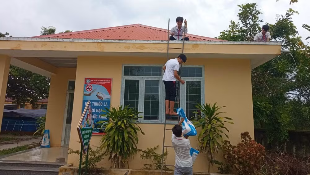 Học sinh tại Quảng Bình tham gia chèn mái tôn trường học để hạn chế thiệt hại do gió bão. 
