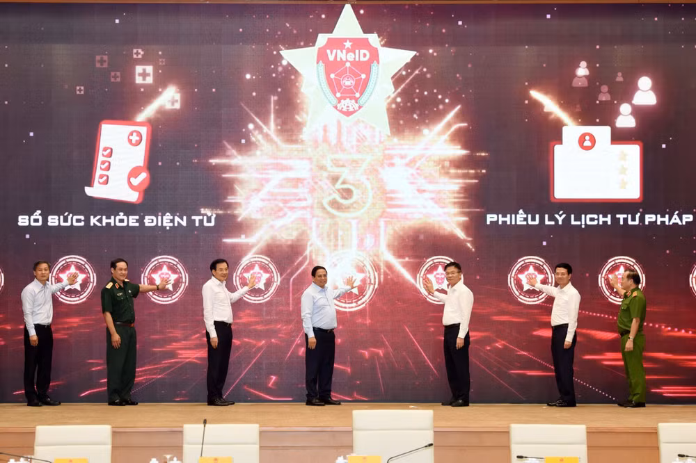 Thủ tướng Phạm Minh Chính và các đồng chí lãnh đạo thực hiện nghi thức kích hoạt triển khai mở rộng thí điểm Sổ sức khỏe điện tử và cấp Phiếu lý lịch tư pháp qua VNeID trên toàn quốc.