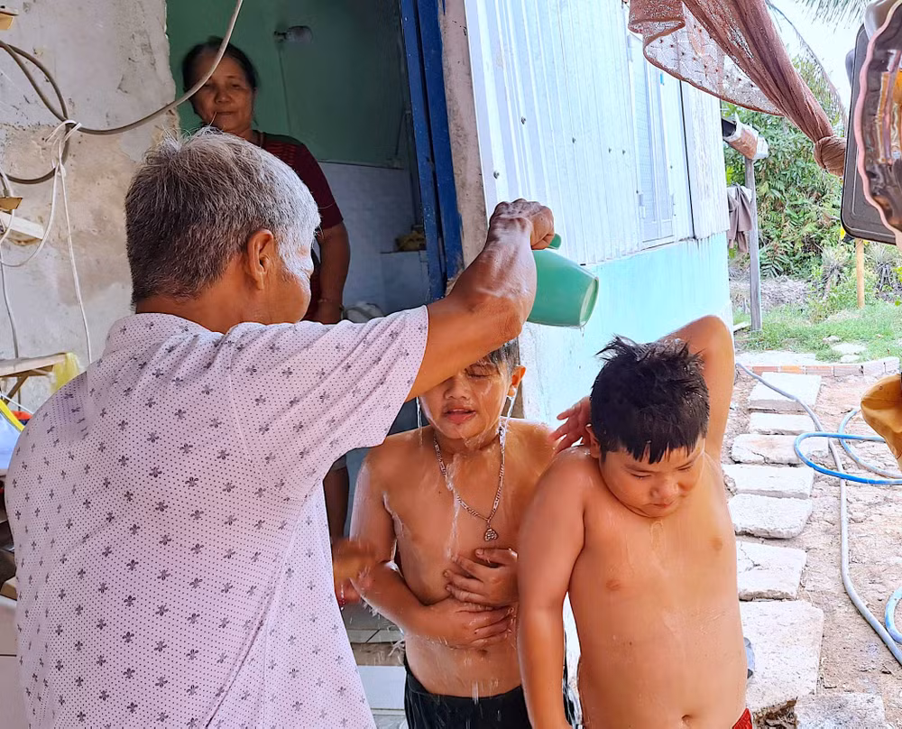Bé Tuấn Khải, Tuấn Quy (ấp Minh Hà B) được người nhà dội rửa lại bằng ít nước ngọt sau khi tắm nước mặn dưới vuông tôm.