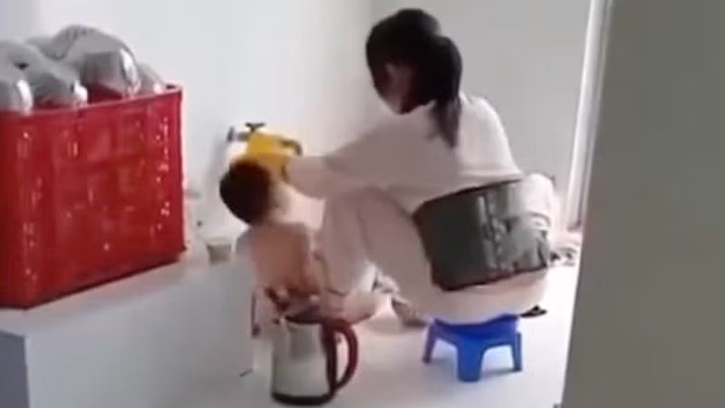 Hình ảnh bảo mẫu đổ thức ăn vào miệng trẻ lan truyền trên mạng xã hội. (Ảnh: Cắt ra từ clip)