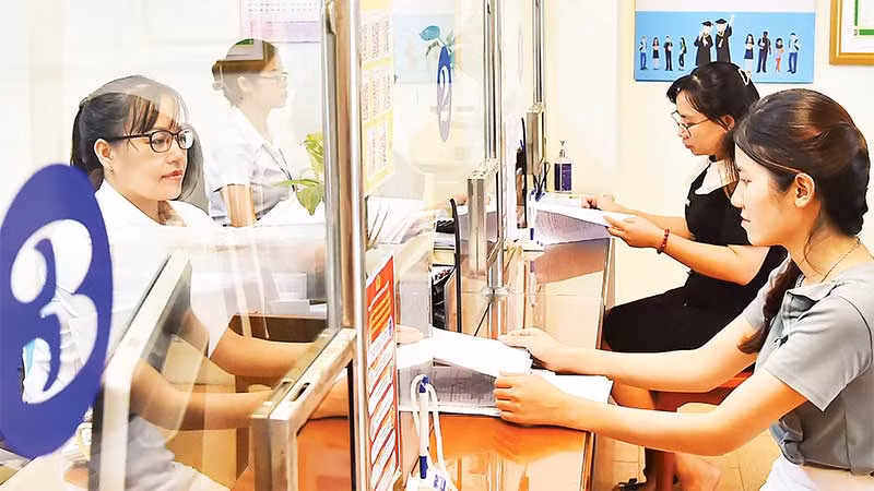 Cán bộ Bộ phận một cửa phường Thanh Xuân Nam, quận Thanh Xuân giải quyết thủ tục hành chính cho người dân. (Ảnh MỸ HÀ)