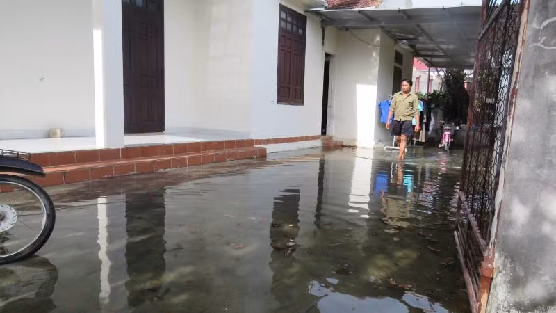 Sân nhà người dân ở Linh Cận Sơn, xã Quảng Sơn, thị xã Ba Đồn bị ngập trong mùa hè do nước công trình thủy lợi tràn vào.