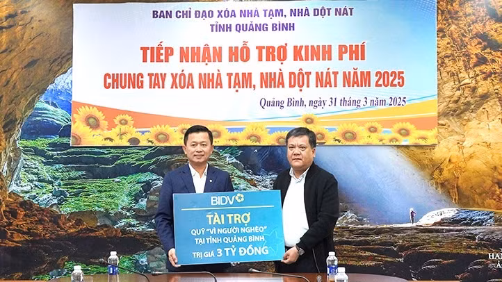 Chủ tịch Ủy ban nhân dân tỉnh Quảng Bình Trần Phong (bên phải) tiếp nhận hỗ trợ của BIDV để xóa nhà tạm, nhà dột nát cho hộ nghèo