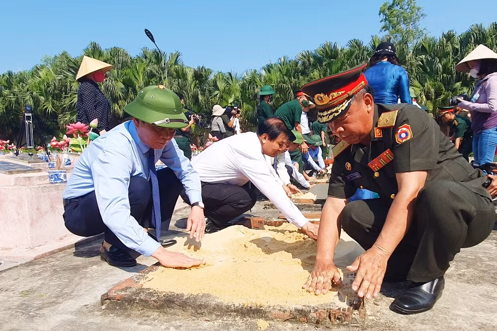 Các đại biểu làm nghi thức đắp đất cát trên mộ phần các liệt sĩ.