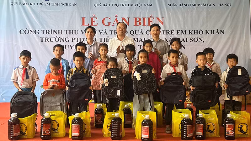 Đại diện Quỹ Bảo trợ trẻ em Việt Nam, các nhà hảo tâm tặng quà cho học sinh có hoàn cảnh khó khăn của Trường Phổ thông dân tộc bán trú tiểu học Mai Sơn. (Ảnh NFVC)
