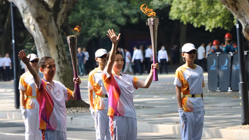 Thành viên rước đuốc ASIAD 19 vẫy tay chào khán giả. (Ảnh: people.com.cn)