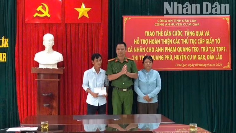 Thượng tá Lê Văn Khánh, Phó Trưởng Công an huyện Cư M'gar trao căn cước công dân và số tiền do cán bộ, chiến sĩ Công an huyện quyên góp tặng cho vợ chồng anh Phạm Quang Tèo.