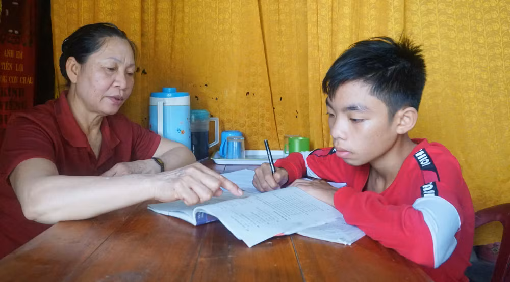 Mẹ đỡ đầu Trương Thị Hiển hướng dẫn cháu Cao Xuân Sỹ học bài.