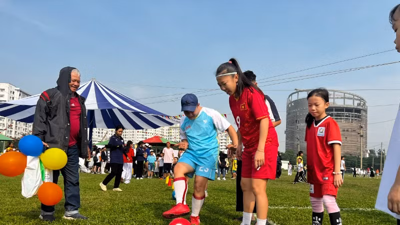 Nữ tuyển thủ quốc gia Huỳnh Như tham gia trò chơi đá bóng cùng các em thiếu nhi.