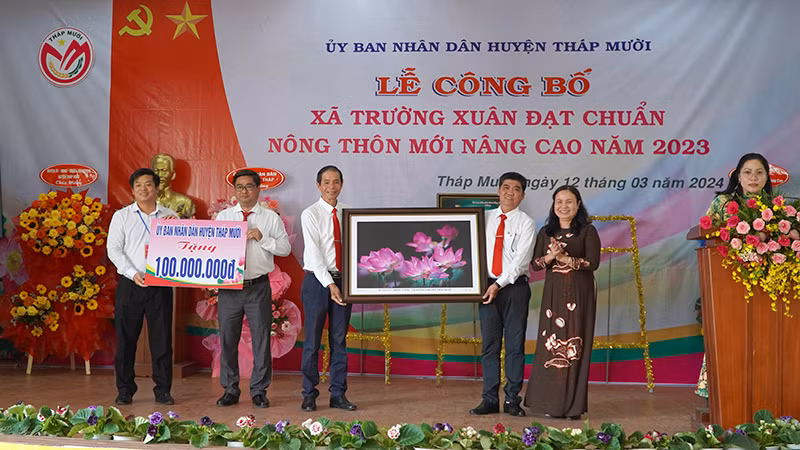 Huyện ủy, Ủy ban nhân dân huyện Tháp Mười tặng quà lưu niệm và 100 triệu đồng cho xã Trường Xuân để thực hiện công trình tại địa phương. (Ảnh: HỮU NGHĨA)