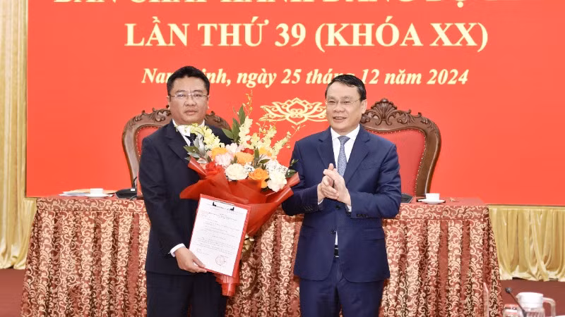 Đồng chí Bí thư Tỉnh ủy Nam Định Đặng Khánh Toàn trao Quyết định của Ban Bí thư Trung ương Đảng cho đồng chí Doãn Quang Hùng (ảnh trái). (Ảnh: XUÂN TRƯỜNG)