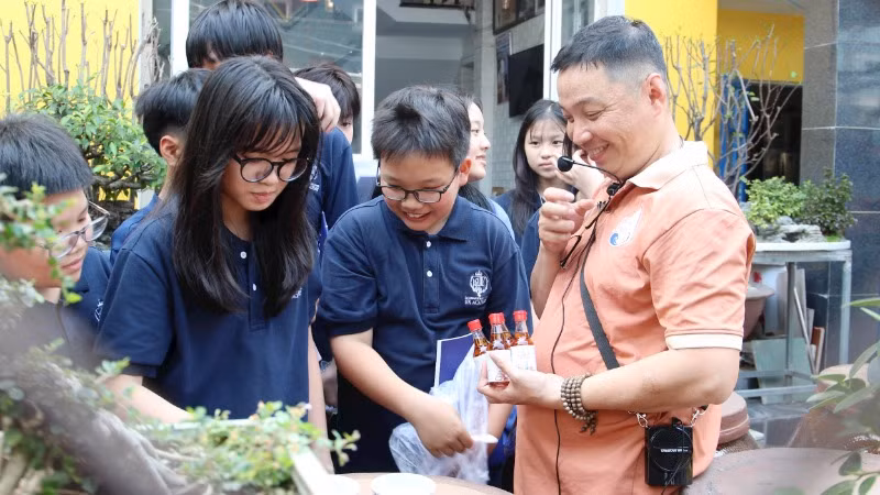 Anh Bùi Thanh Phú (ngoài cùng bên phải) giới thiệu với học sinh về nghề làm nước mắm.