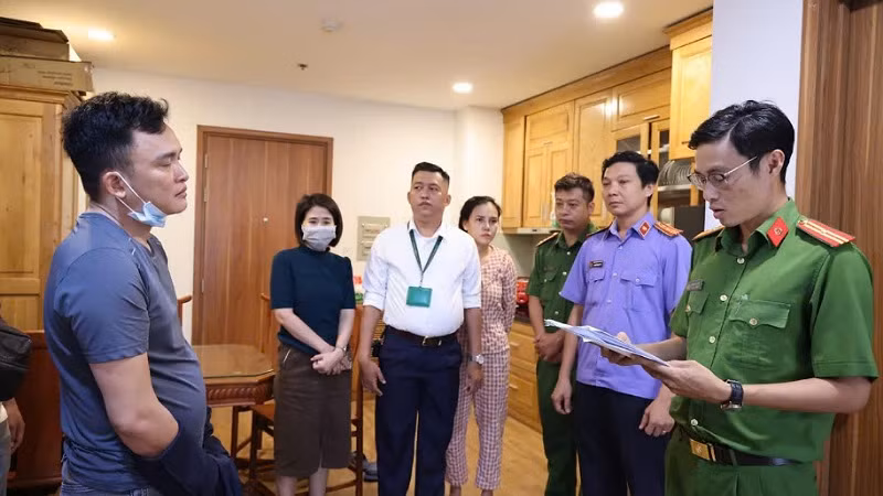 Lực lượng chức năng đọc lệnh khám xét và bắt tạm giam bị can.
