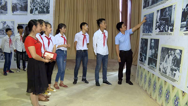 Các em học sinh nghe giới thiệu về những hình ảnh lịch sử tại Đại hội II.