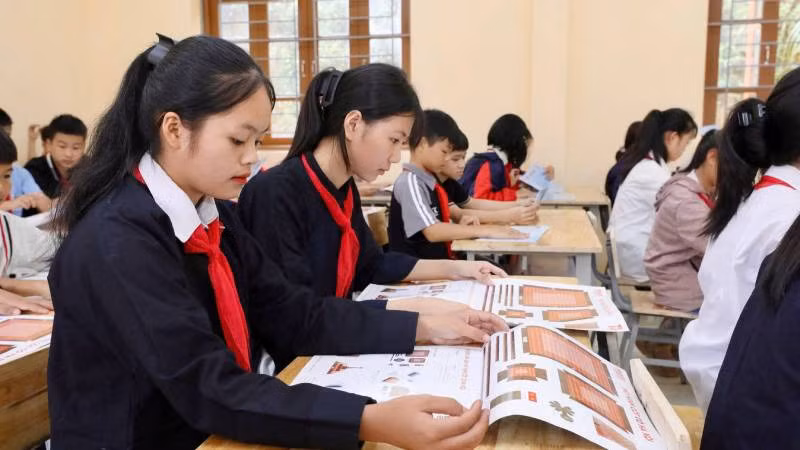 Các em học sinh trường Trung học cơ sở Tân Văn, huyện Bình Gia (Lạng Sơn), tiếp nhận ấn phẩm đặc biệt " Cột cờ Hà Nội".