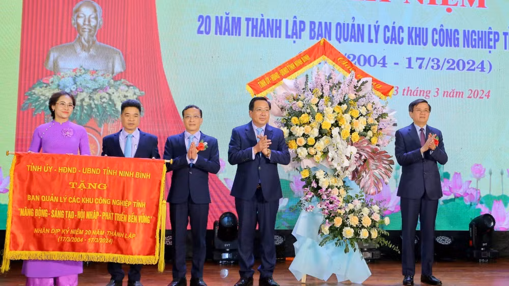 Đồng chí Bí thư Tỉnh ủy Ninh Bình Đoàn Minh Huấn đã trao bức trướng với dòng chữ "Năng động-sáng tạo-hội nhập-phát triển bền vững" và tặng hoa cho Ban Quản lý các khu công nghiệp tỉnh. (Ảnh: ANH TUẤN)