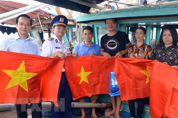 Tặng cờ Tổ quốc cho bà con ngư dân huyện Cát Hải. (Ảnh: TTXVN)