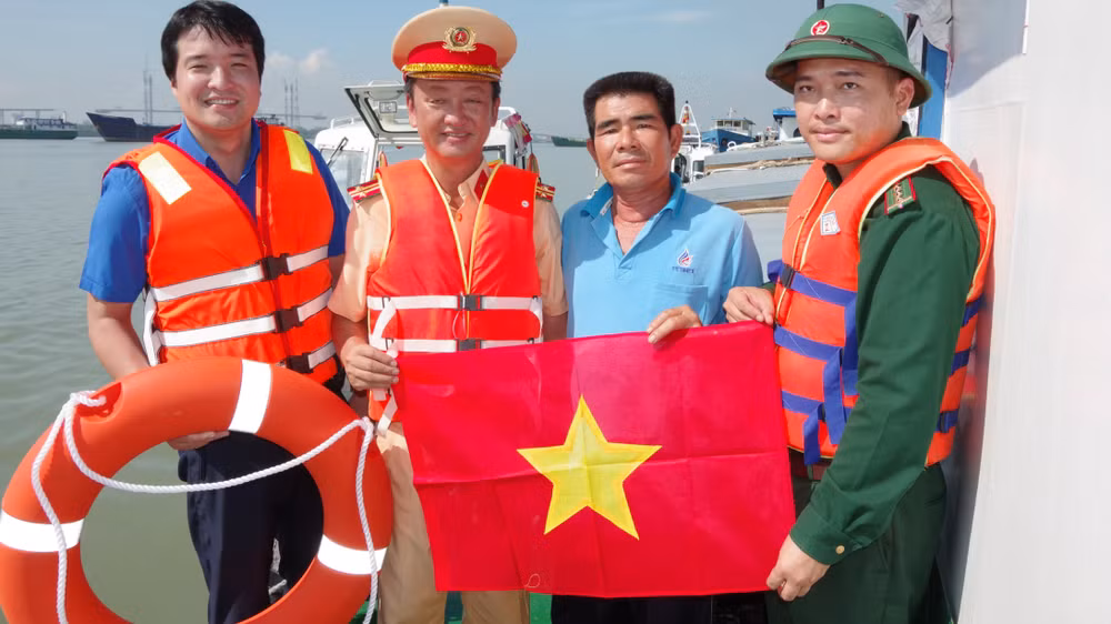 Các đơn vị phối hợp cùng phát tờ rơi, tặng áo phao cá nhân và phao cứu sinh cho chủ phương tiện vận tải trên sông Soài Rạp. (Ảnh: Mai Lan)